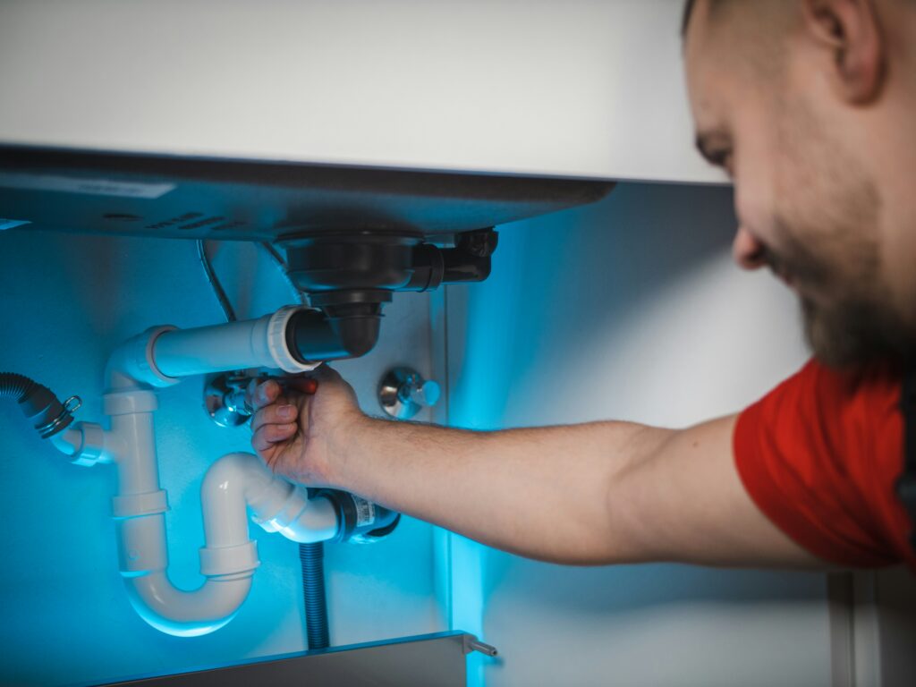 Installateur repariert einen Anschluss unter einem Waschbecken